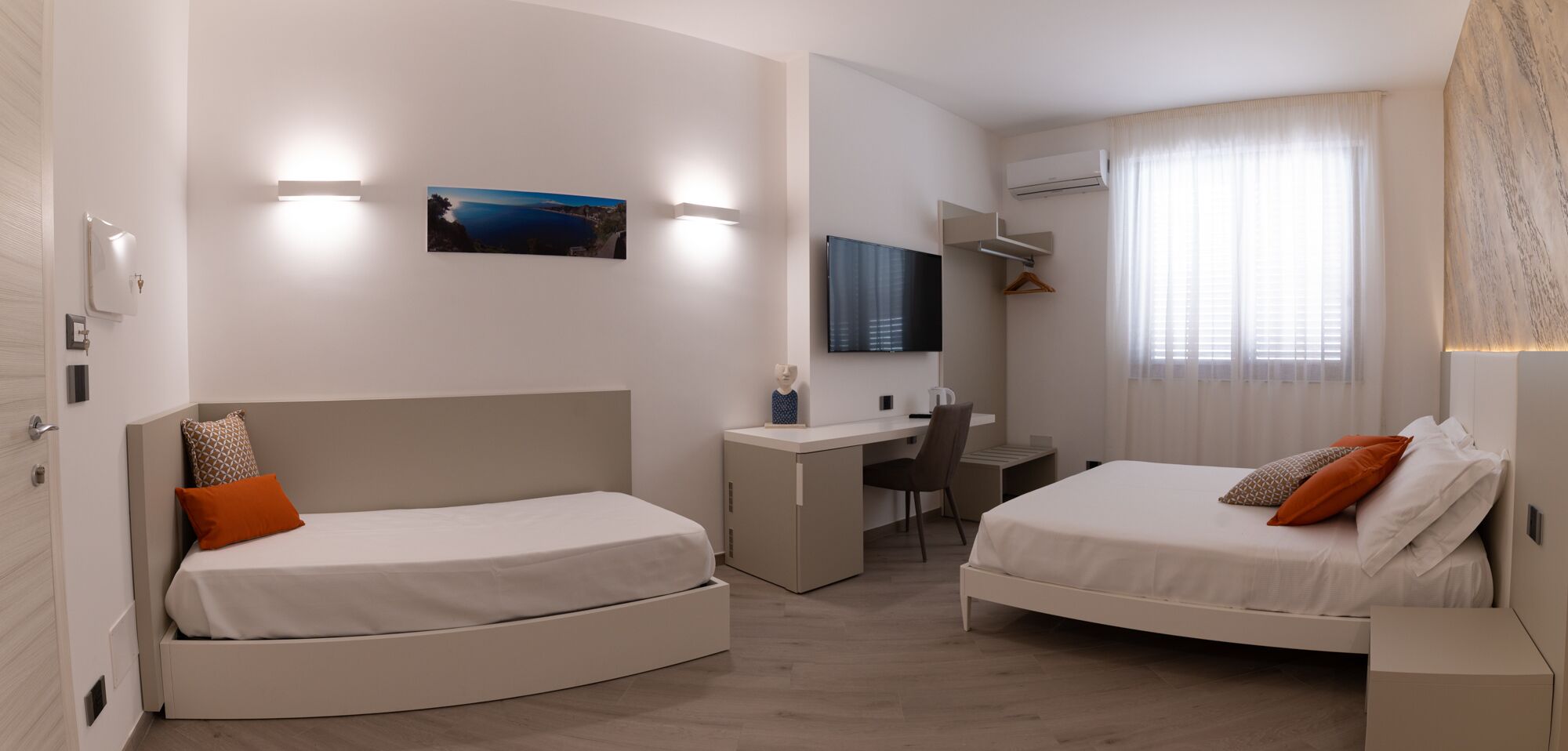 Une chambre d’hôtel moderne avec deux lits, un bureau et une télévision.