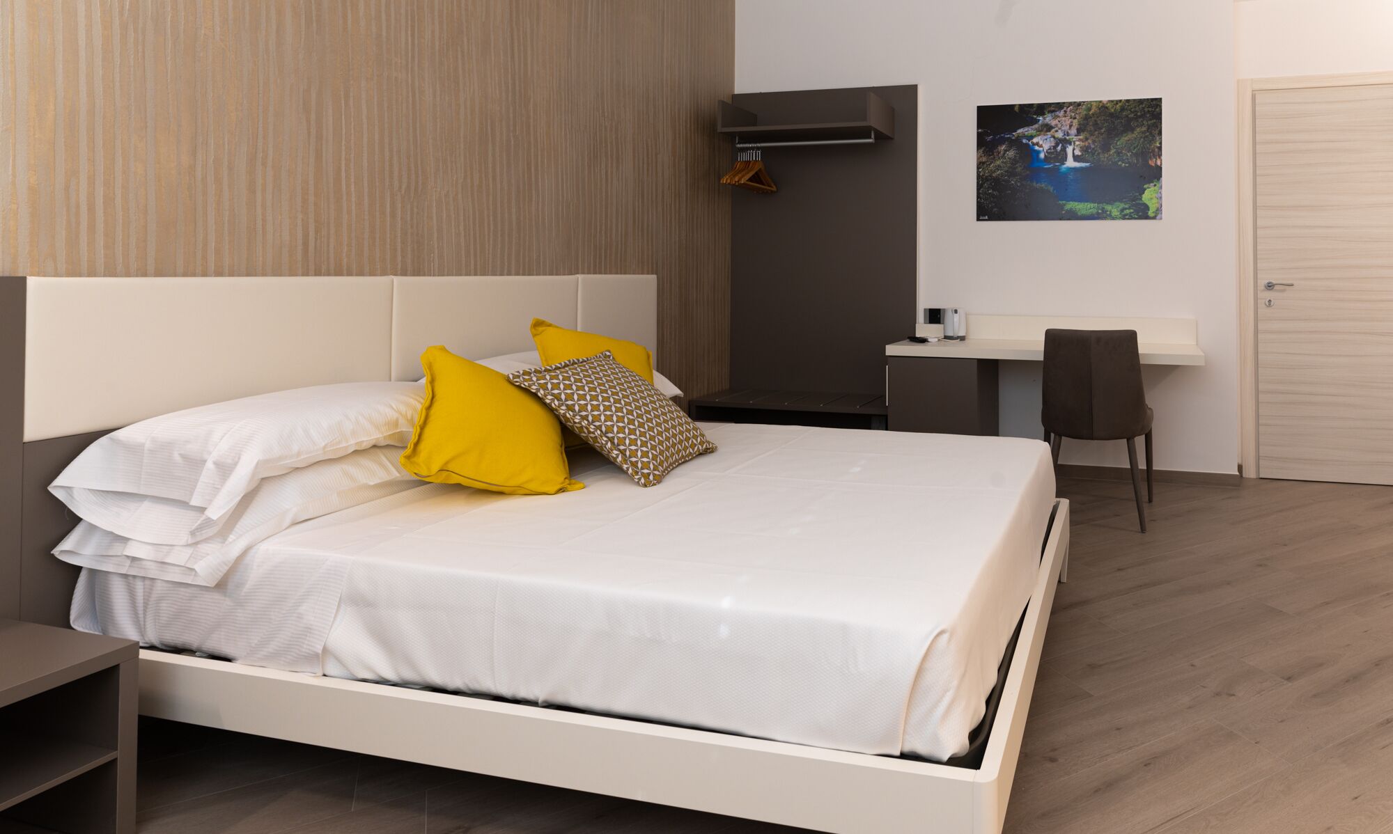 A modern hotel room with a bed, a desk, and a chair.