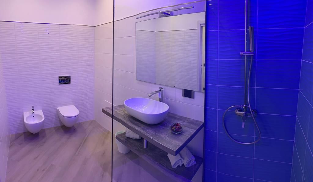 A modern bathroom with a glass shower enclosure, a freestanding bathtub, and a vanity with a mirror.