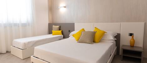 A modern hotel room with a large bed, two bedside tables, and a small table with a vase.