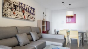 A modern living room with a grey sofa, a glass coffee table, and a dining area with a table and chairs. - First line / Wifi / Spa / Seaviews / Heated pool / Pets (Calpe)