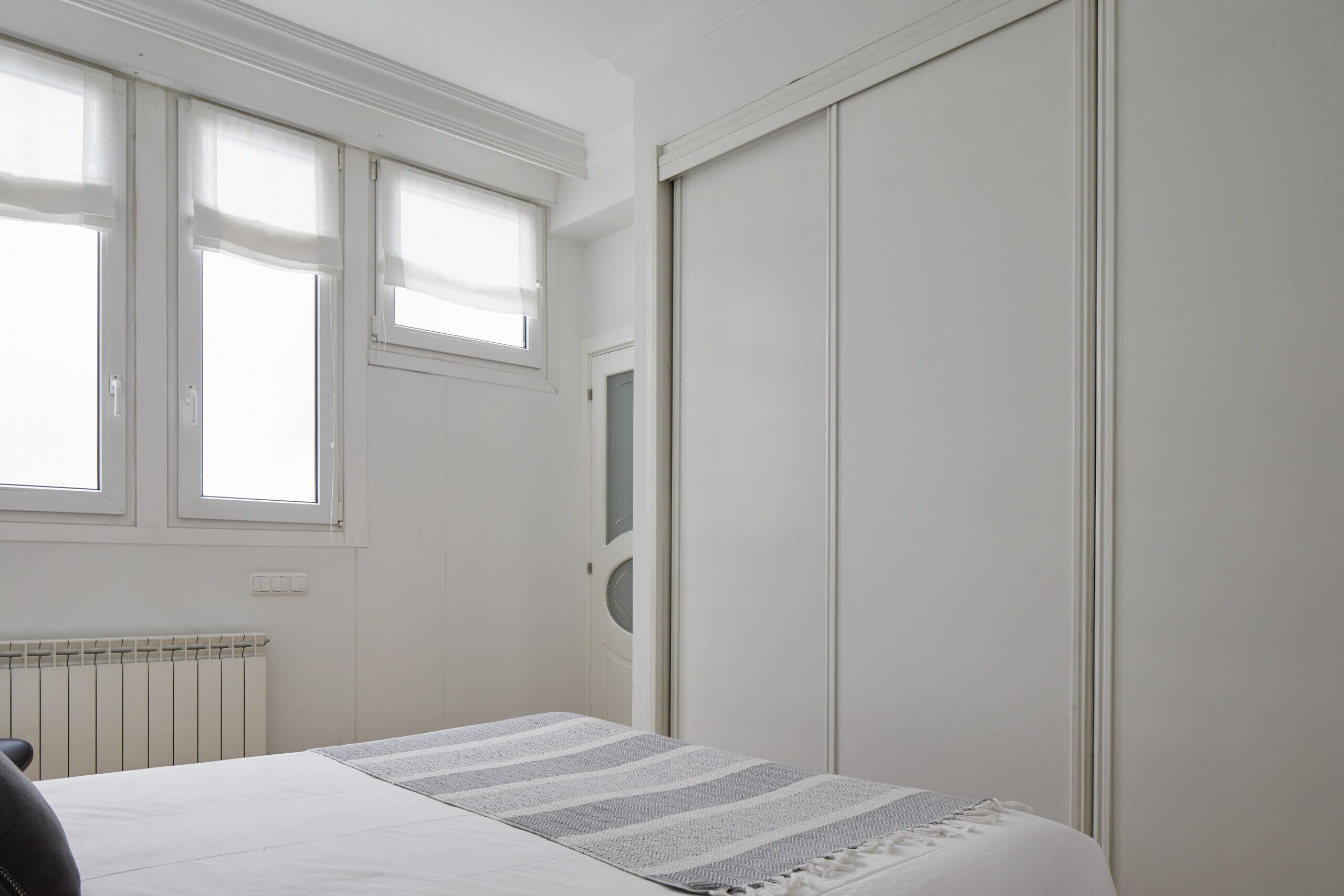 A bedroom with a bed, a radiator, and a window.