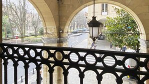 An arched corridor with a street view, a hanging lamp, and a tree.
