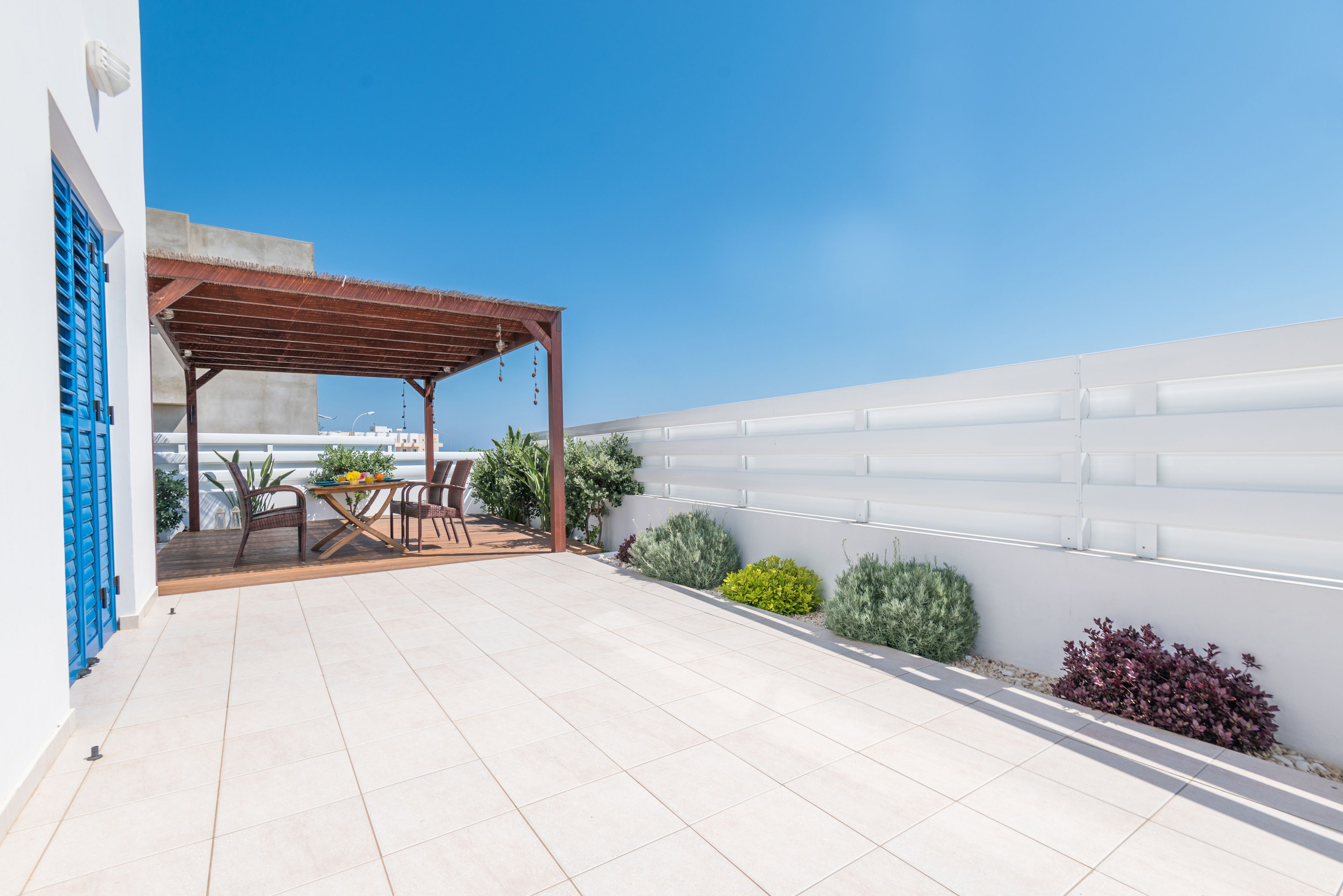 A rooftop terrace with a pergola, outdoor seating, and potted plants.