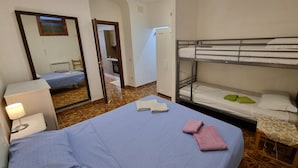 Una camera da letto con un letto a castello, un letto singolo, un comodino con una lampada e uno specchio.