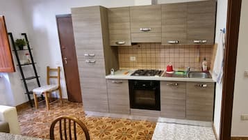 Eine kleine Küche mit Holzausstattung, einem Gasherd und einem Spülbecken.