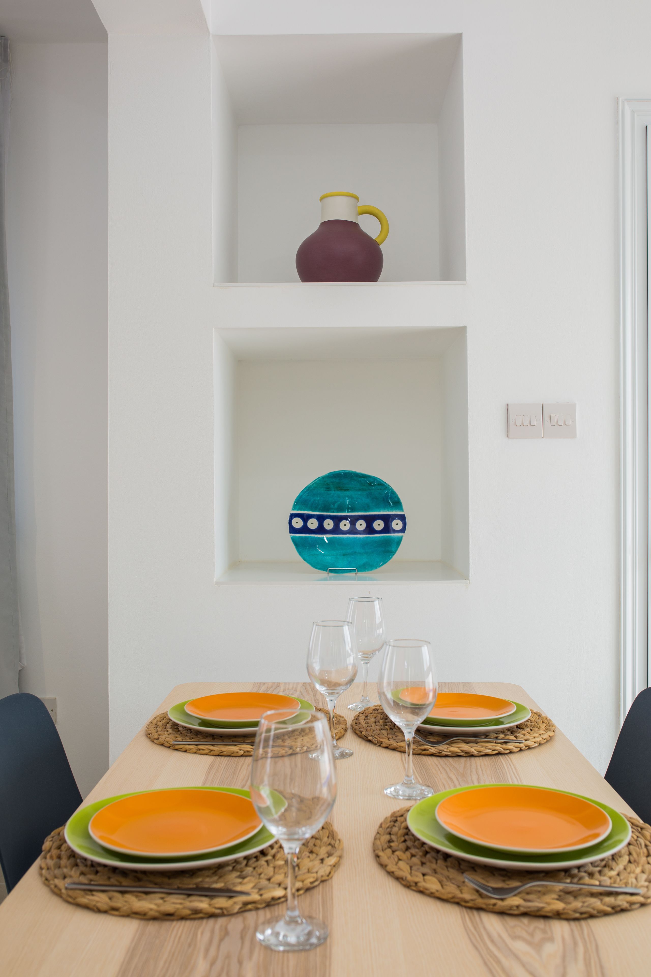 A dining table set with plates, glasses, and placemats.