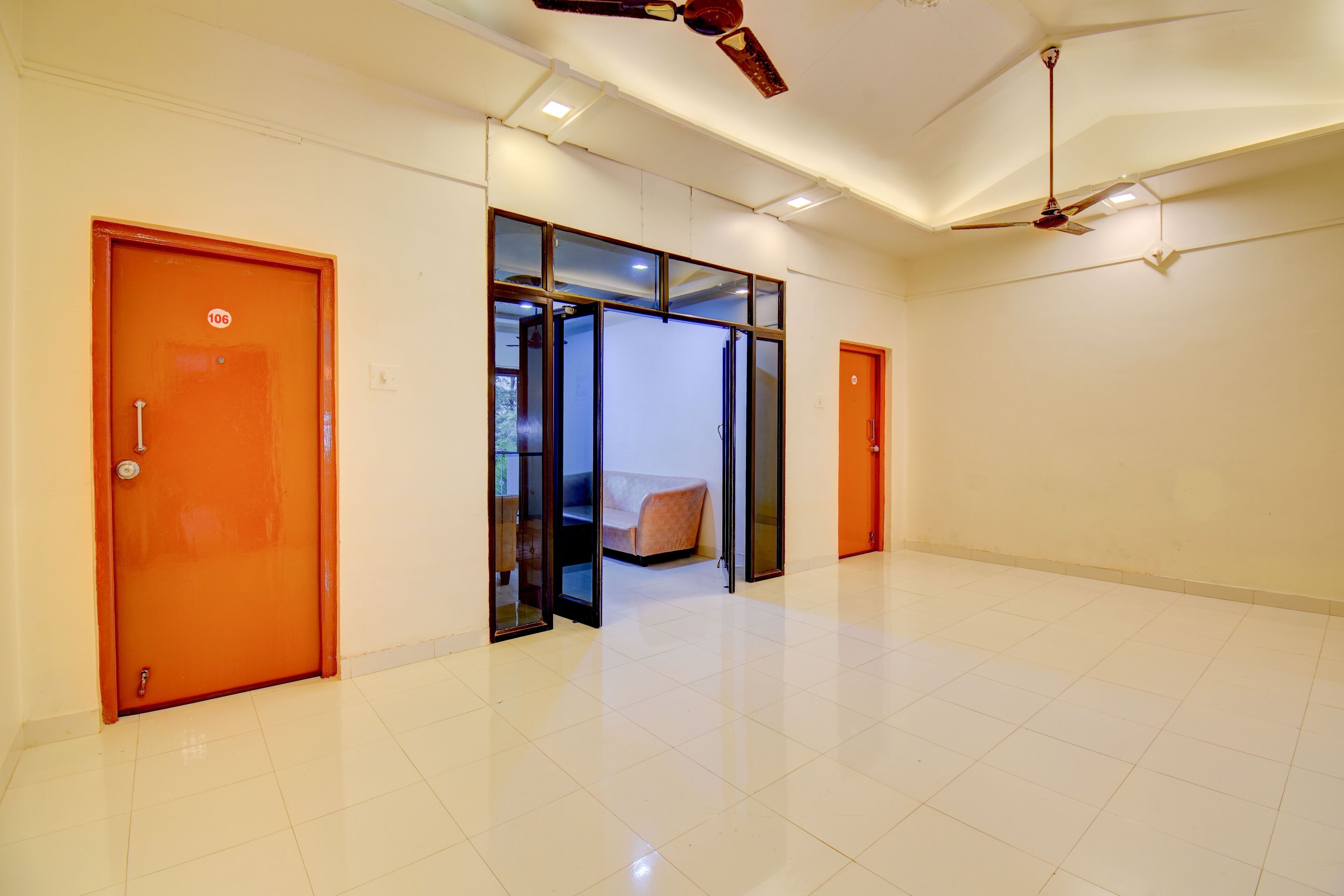 A spacious hallway with a modern design, featuring a glass partition, a seating area, and a ceiling fan.