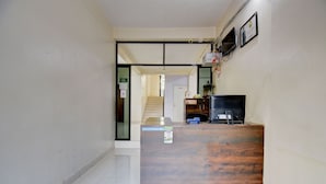 Un comptoir d’accueil avec un revêtement en bois, un téléviseur et un certificat encadré accroché au mur.