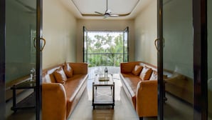 Un salon moderne avec deux canapés en cuir, une table basse en verre et un ventilateur de plafond.