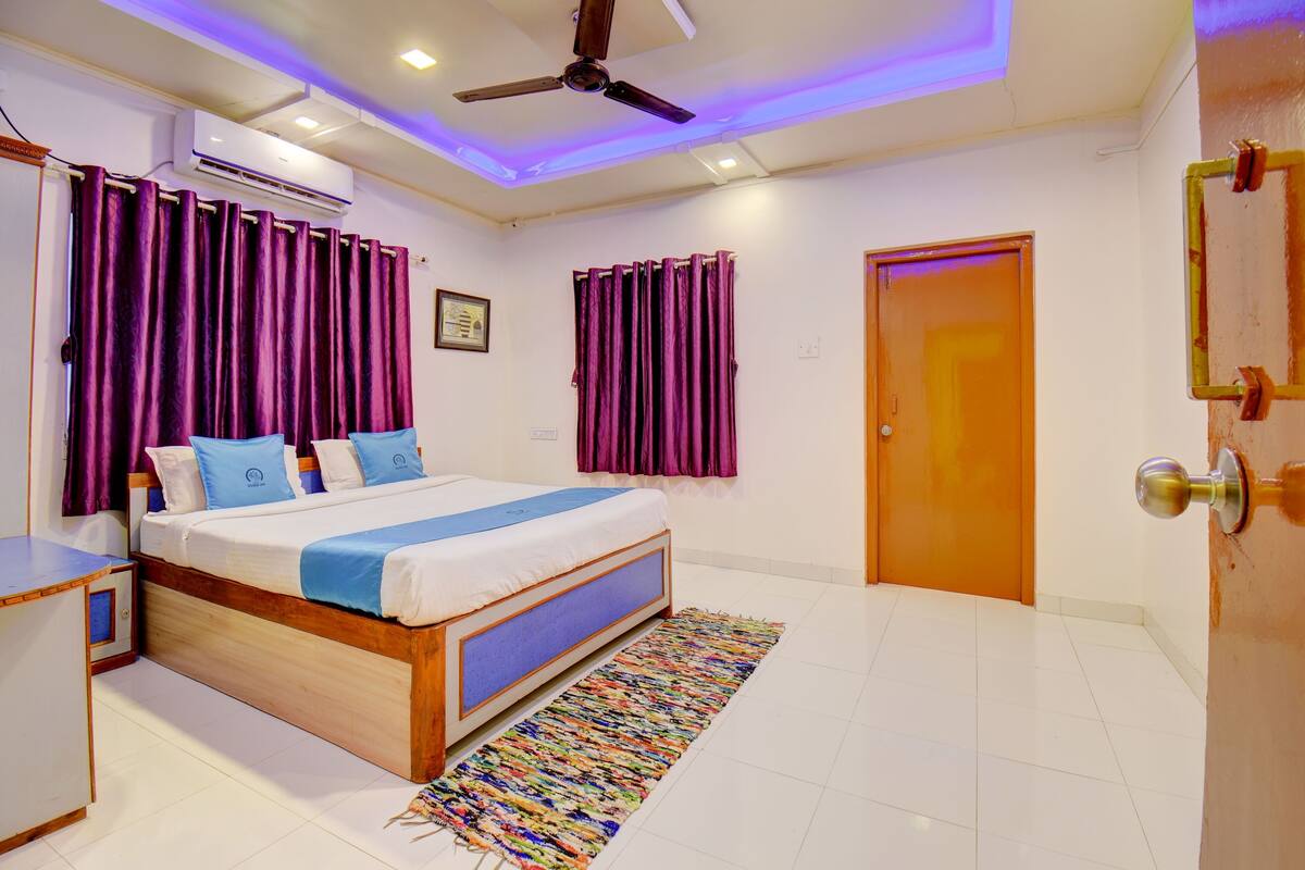 Une chambre à coucher avec un lit, des rideaux, un ventilateur de plafond, un climatiseur et une porte.