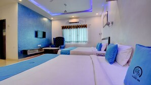 Une chambre d’hôtel avec deux lits, un bureau, une chaise, un ventilateur de plafond et une fenêtre avec des rideaux.