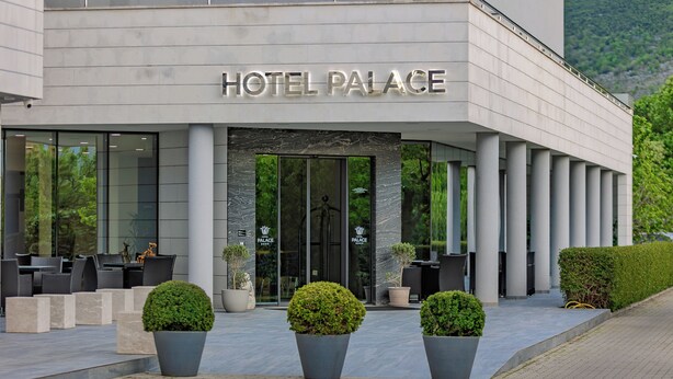 A hotel with a modern facade, large glass entrance, and outdoor seating area. - Hotel Palace Medjugorje (Citluk)