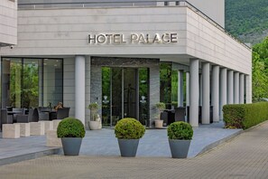 A hotel with a modern facade, large glass entrance, and outdoor seating area. - Hotel Palace Medjugorje (Citluk)