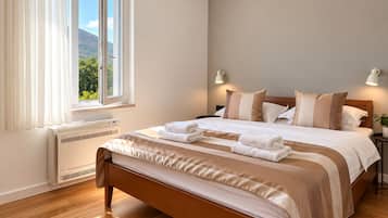 Ein Schlafzimmer mit einem Bett, Nachttischlampen, einem Fenster mit Vorhängen und einer Heizung.