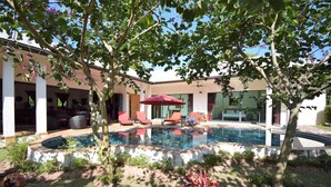 A modern outdoor pool area with a hot tub, surrounded by a covered patio with red chairs and a red umbrella. - 4 Bedroom Villa with Private Pool in Walled Garden (Mae Nam)