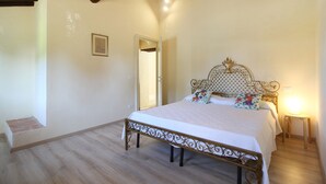 A bedroom with a bed, wooden floor, and a ceiling with exposed beams. - Lovely cottage in the park of a Renaissance Villa (Capannori)