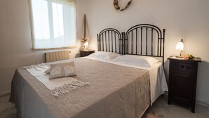 Ein Schlafzimmer mit einem Bett, einem Nachttisch, einer Lampe, einem Fenster mit Vorhängen und einer Wanddekoration.