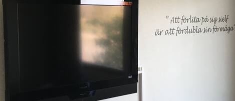 Un televisor de pantalla plana montado en la pared con una cita en idioma extranjero.