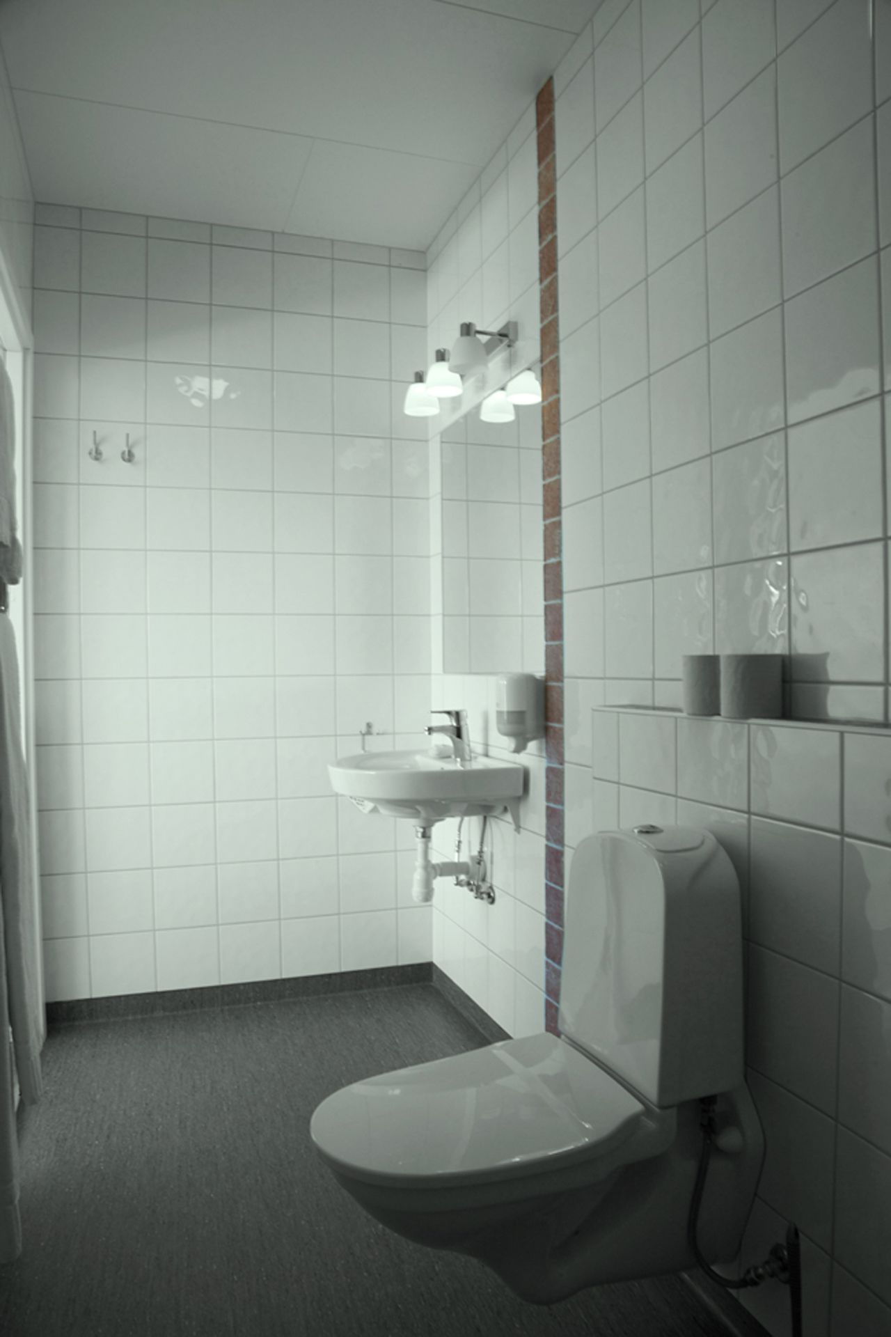 Een moderne badkamer met een wit wastafelmeubel, toilet en douchehoek.