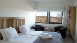 Une chambre d’hôtel avec un lit, deux chaises, une petite table et une vue sur l’extérieur.