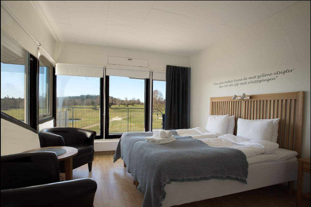 Une chambre d’hôtel avec un grand lit, un bureau, une chaise et une vue sur un terrain de golf.