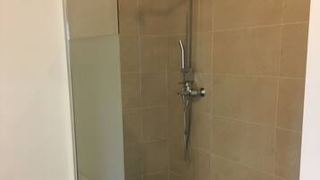A glass-enclosed shower with a black base, tiled walls, and a tiled floor.