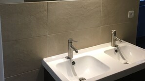 Ein Badezimmer mit zwei Waschbecken, einem Spiegel und einer Dusche.