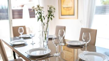 Una mesa de comedor dispuesta con platos, vasos y cubiertos, con sillas alrededor.