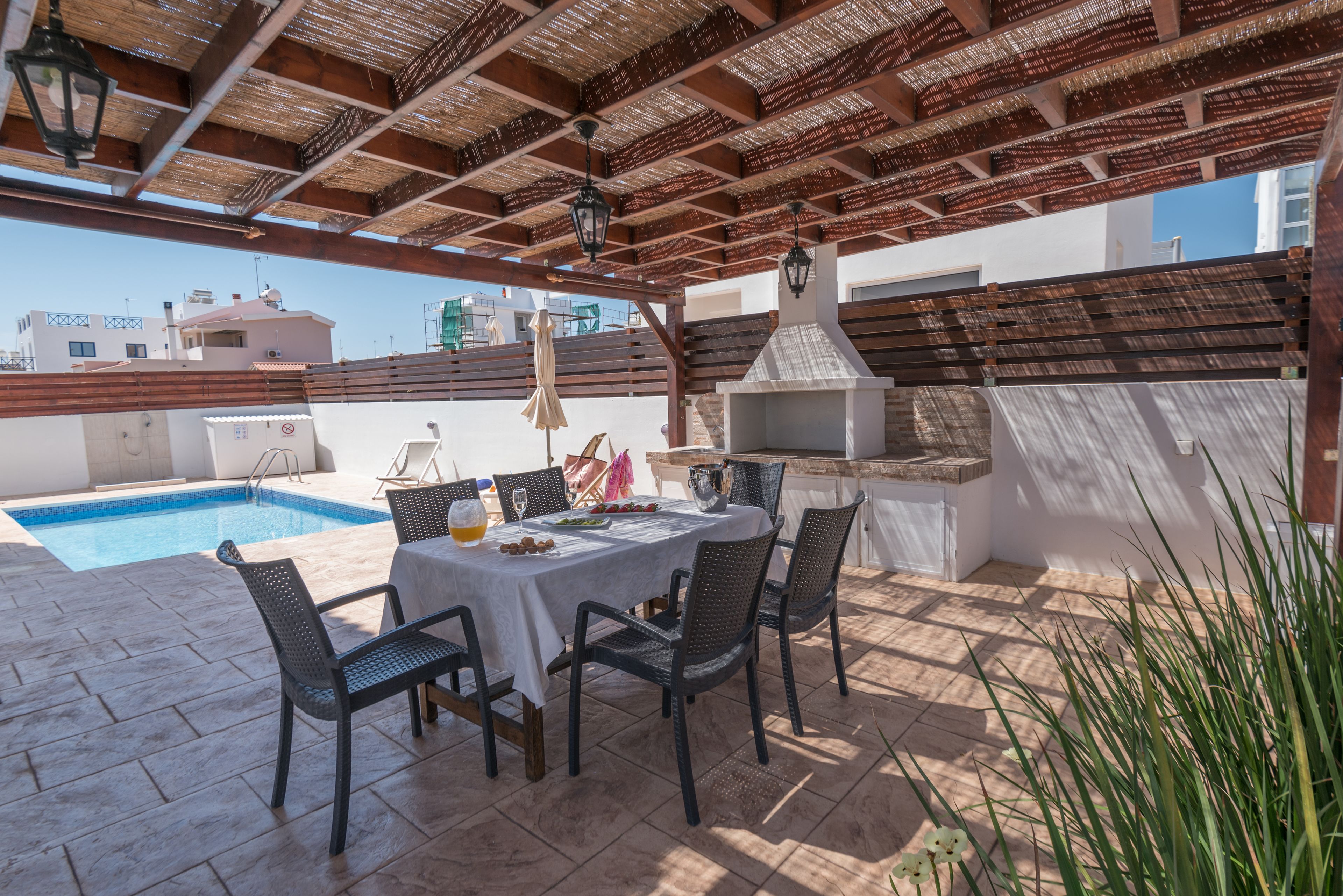 A rooftop patio with a pool, outdoor seating, and a barbecue area.