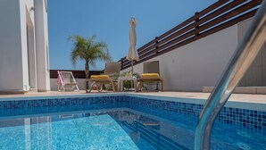 A clear blue pool with lounge chairs and a palm tree. - Narcissos Villa 2 (Paralimni)