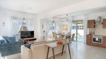 Una sala de estar moderna con sofá, televisor y comedor.