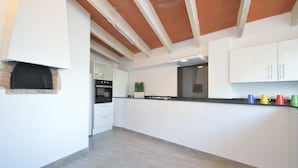 Una cocina moderna con armarios blancos, encimera negra y techo de madera.