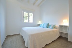 Un dormitorio con una cama grande, dos lámparas de noche, una ventana y una mesita de noche.
