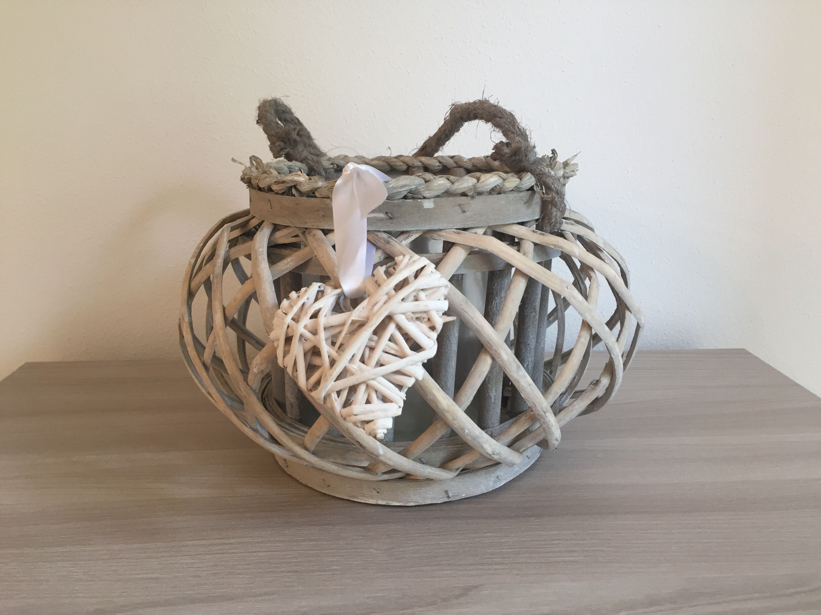 A woven basket with a handle, placed on a wooden surface.