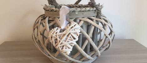 A woven basket with a handle, placed on a wooden surface.
