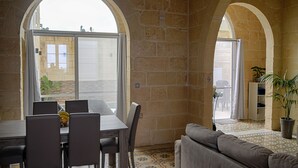 A dining area with a table and chairs, a sofa, and a potted plant. - Simar Farmhouse (Qala)