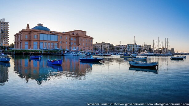 A marina with boats docked in front of a large building with a dome.
