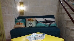 A room with a teal sofa set, a yellow table, and a decorative fish bowl.