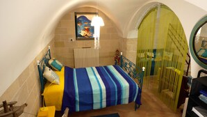 A bedroom with a bed, a radiator, a window, and a door.