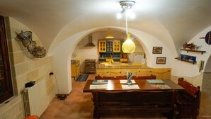 A dining area with a wooden table, benches, and a hanging light fixture.