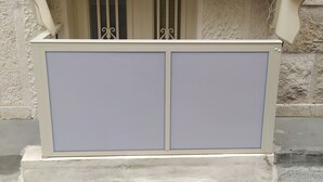 A small, enclosed outdoor seating area with a light-colored awning and two cabinets.
