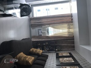 Relax in this stylish living room with a sofa, floor with a unique pattern, and a glass wall offering a view.