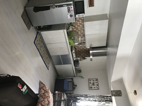 Enjoy cooking in this well-equipped kitchen with a microwave, oven, and range hood, adjacent to a cozy living area with a sofa and coffee table.