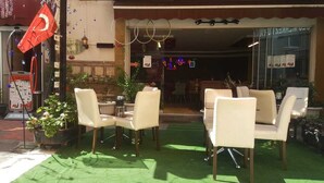 An outdoor seating area with chairs and tables, a potted plant, and a flag. - Carsi Otel (Trabzon)