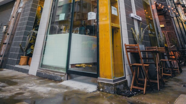 A modern building with a glass storefront and outdoor seating. - Kactus Hotel (Kowloon)