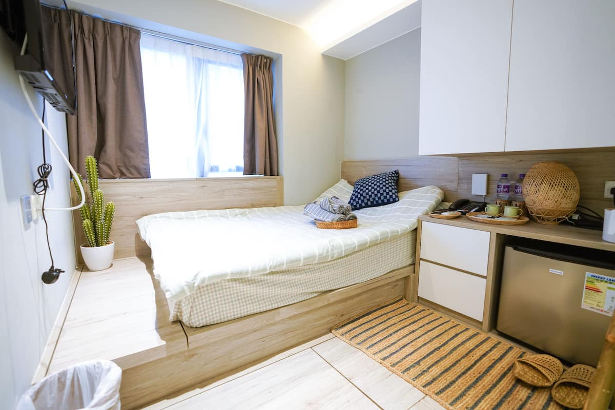 Un dormitorio pequeño con cama, mesita de noche y una kitchenette.