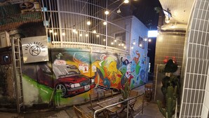 A wall with a colorful mural, a taxi sign, and a cactus plant. - Kactus Hotel (Kowloon)