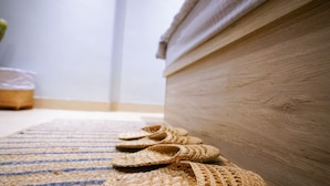 A wooden floor with a woven mat and a pair of woven slippers. - Kactus Hotel (Kowloon)