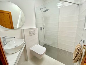 Ein modernes Badezimmer mit Waschbecken, Toilette und Duschkabine aus Glas.